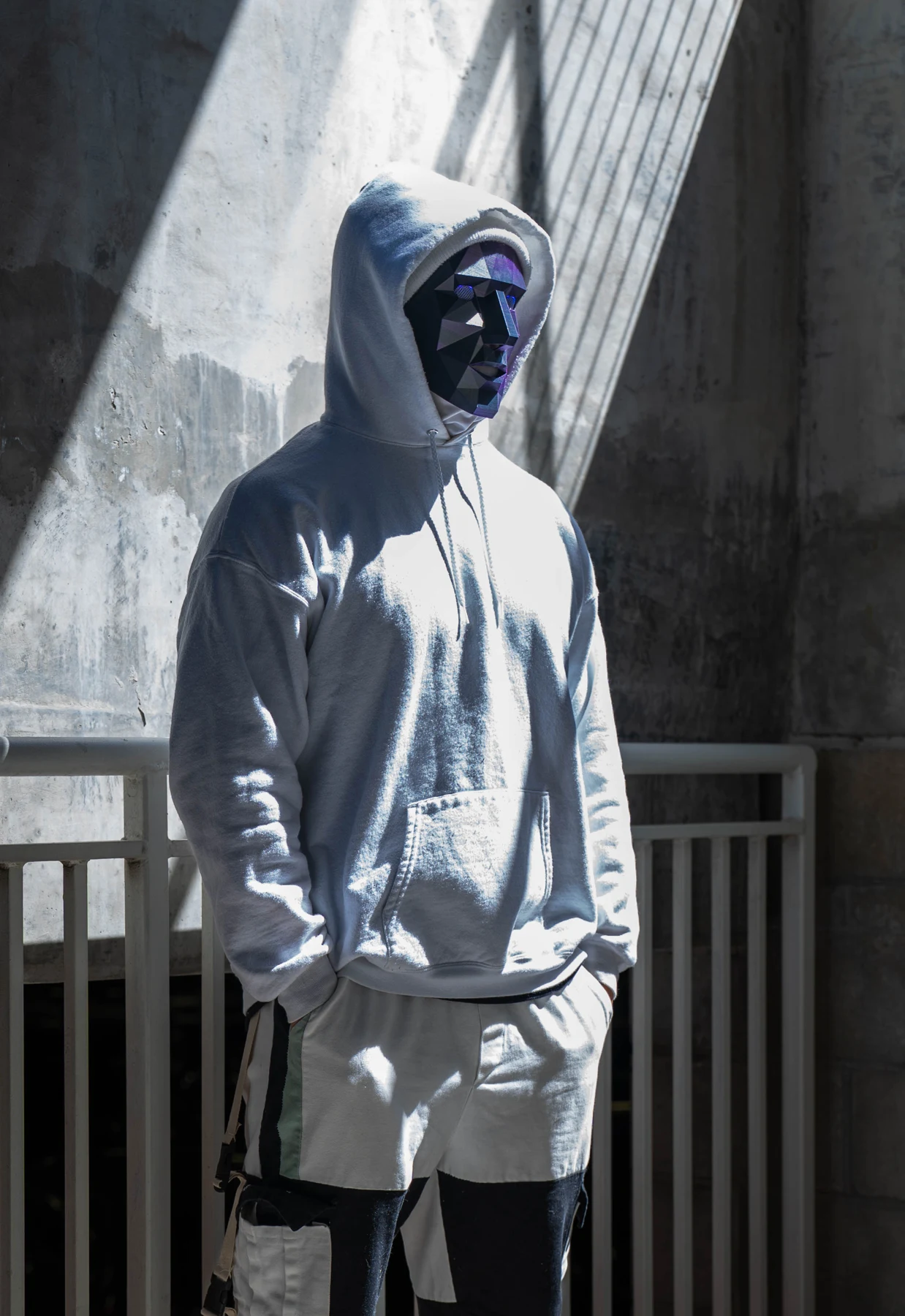 NoFace in a gray hoodie beneath dramatic beams of light