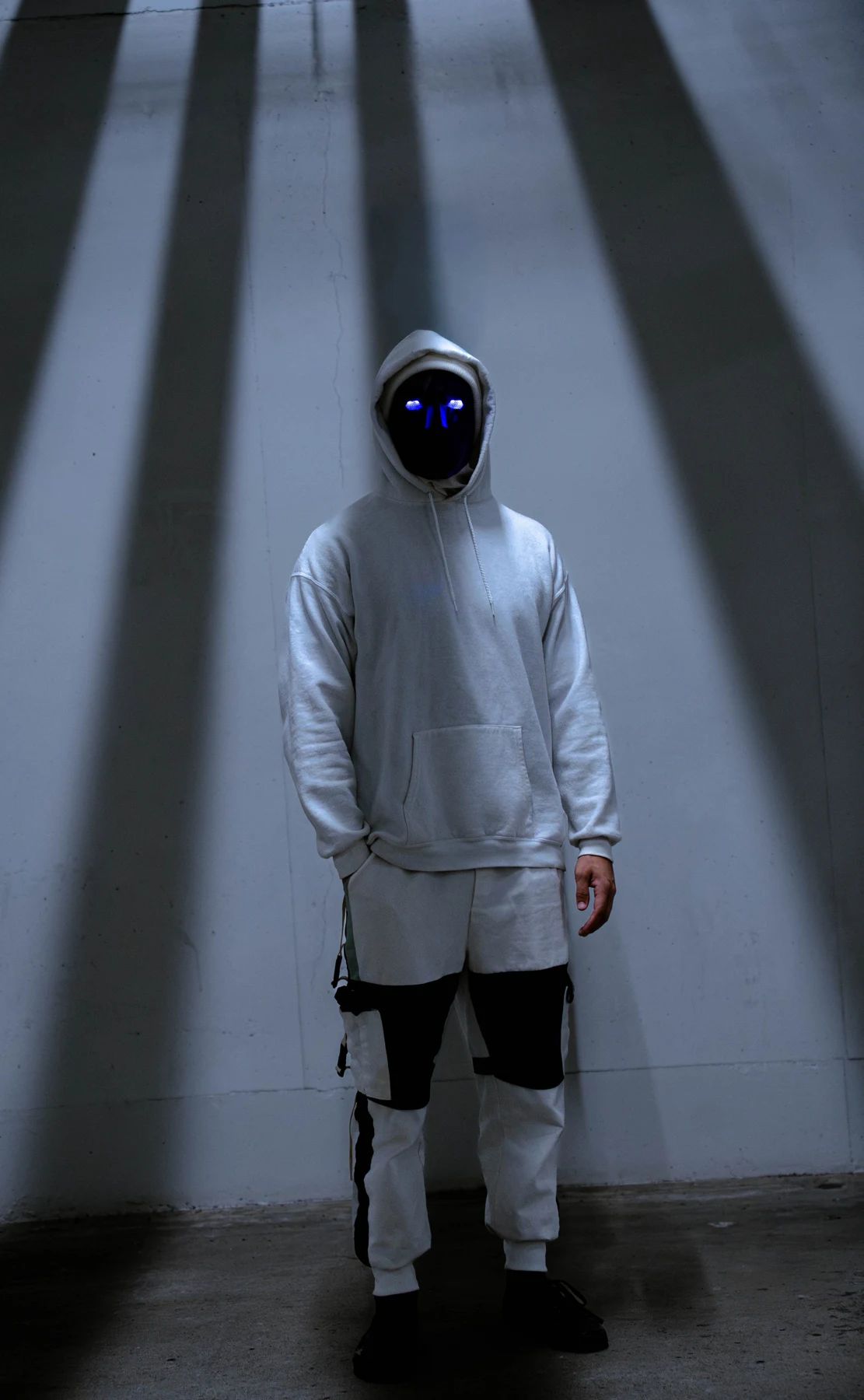 NoFace in a white hoodie wearing a black geometric mask